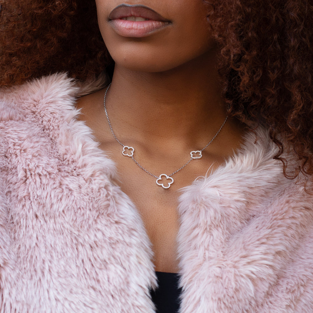 Woman wearing silver four leaf clover necklace. With two small and one large four leaf clovers.