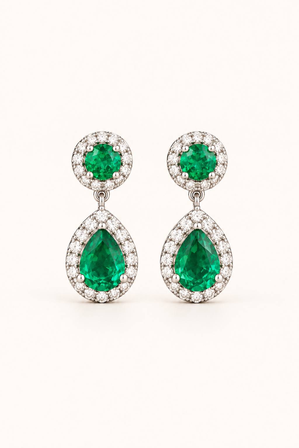 Green halo pear drop earrings in 9ct white gold on a plain cream background