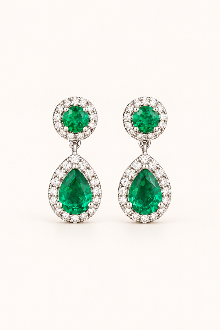 Green halo pear drop earrings in 9ct white gold on a plain cream background