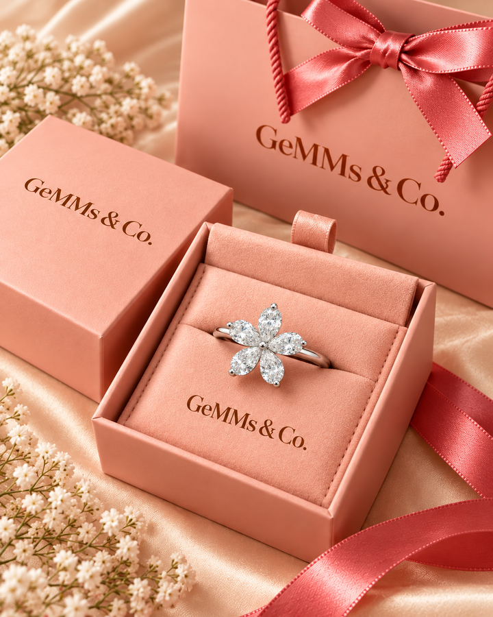Five-petal pear-shaped diamond flower ring in GeMMs & Co blush pink luxury gift packaging — styled illustration